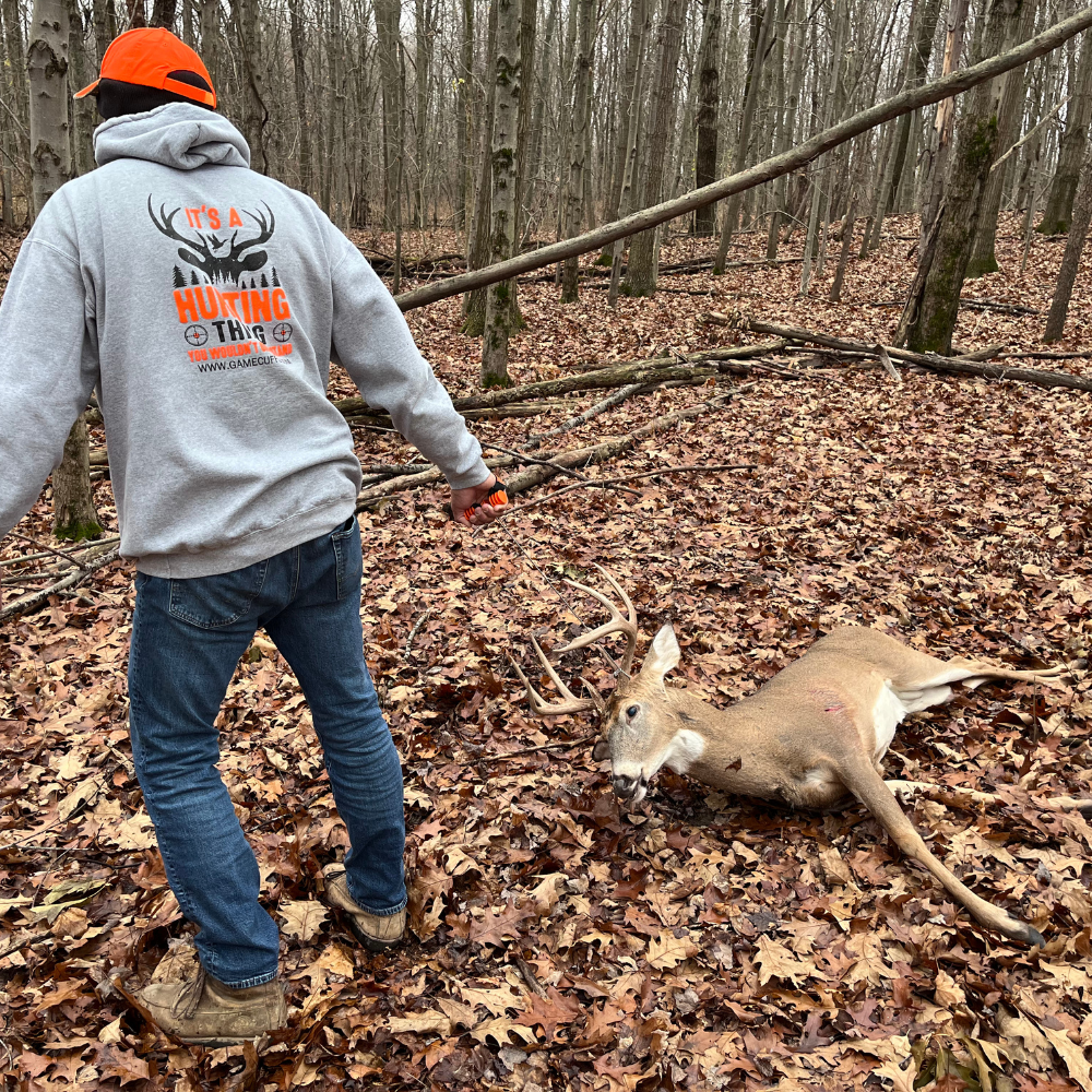 Hunter using orange Buck Cuffs to drag a whitetail deer through the woods